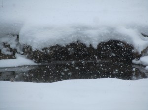 Snow on the side of the creek in front of the Cabin...